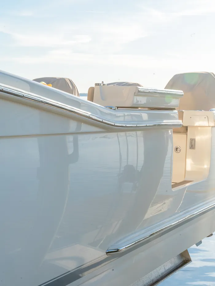 Glossy white deck boat hull side with polished rail